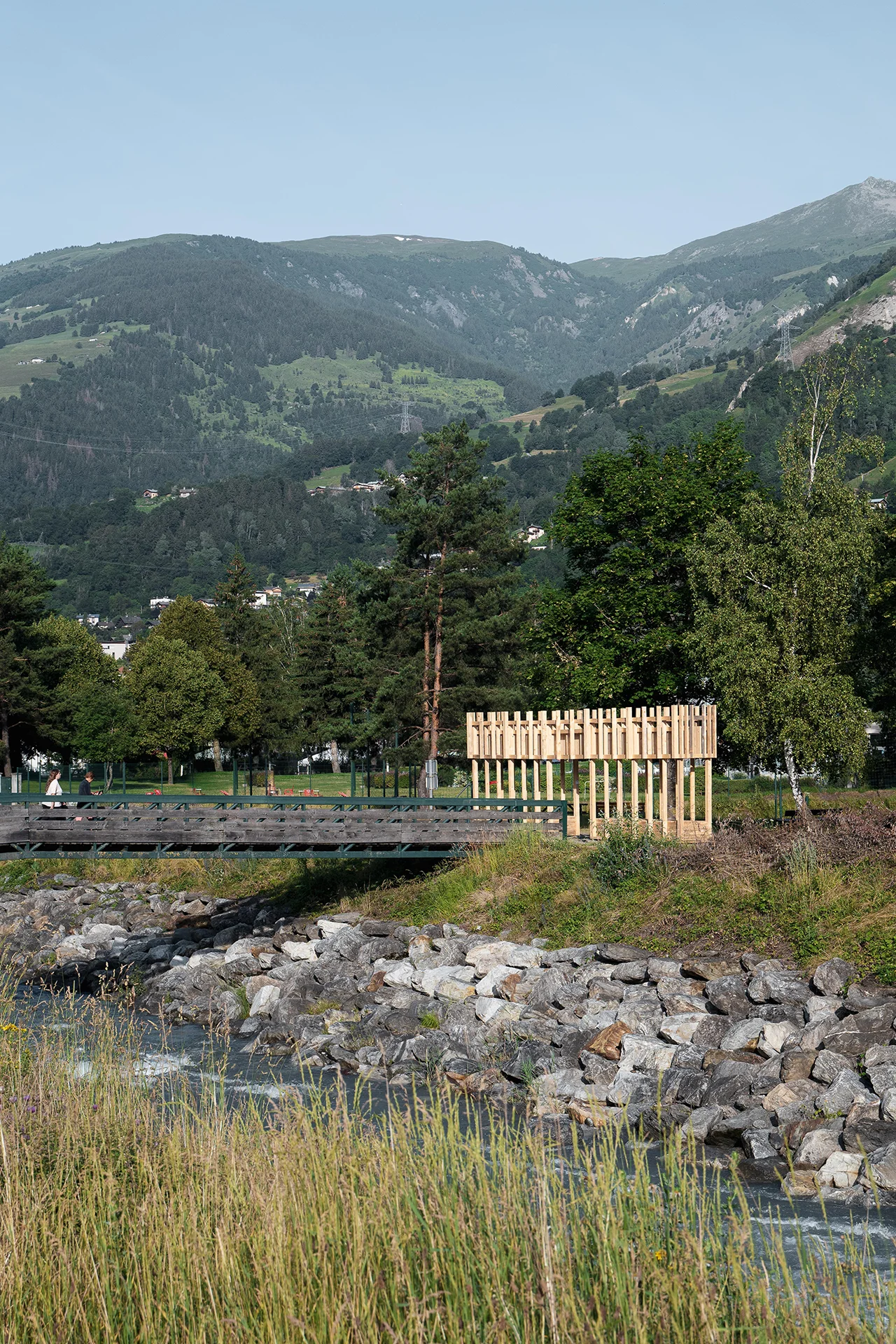 Vue de trois quarts du projet depuis le parc avec personnes sur la passerelle