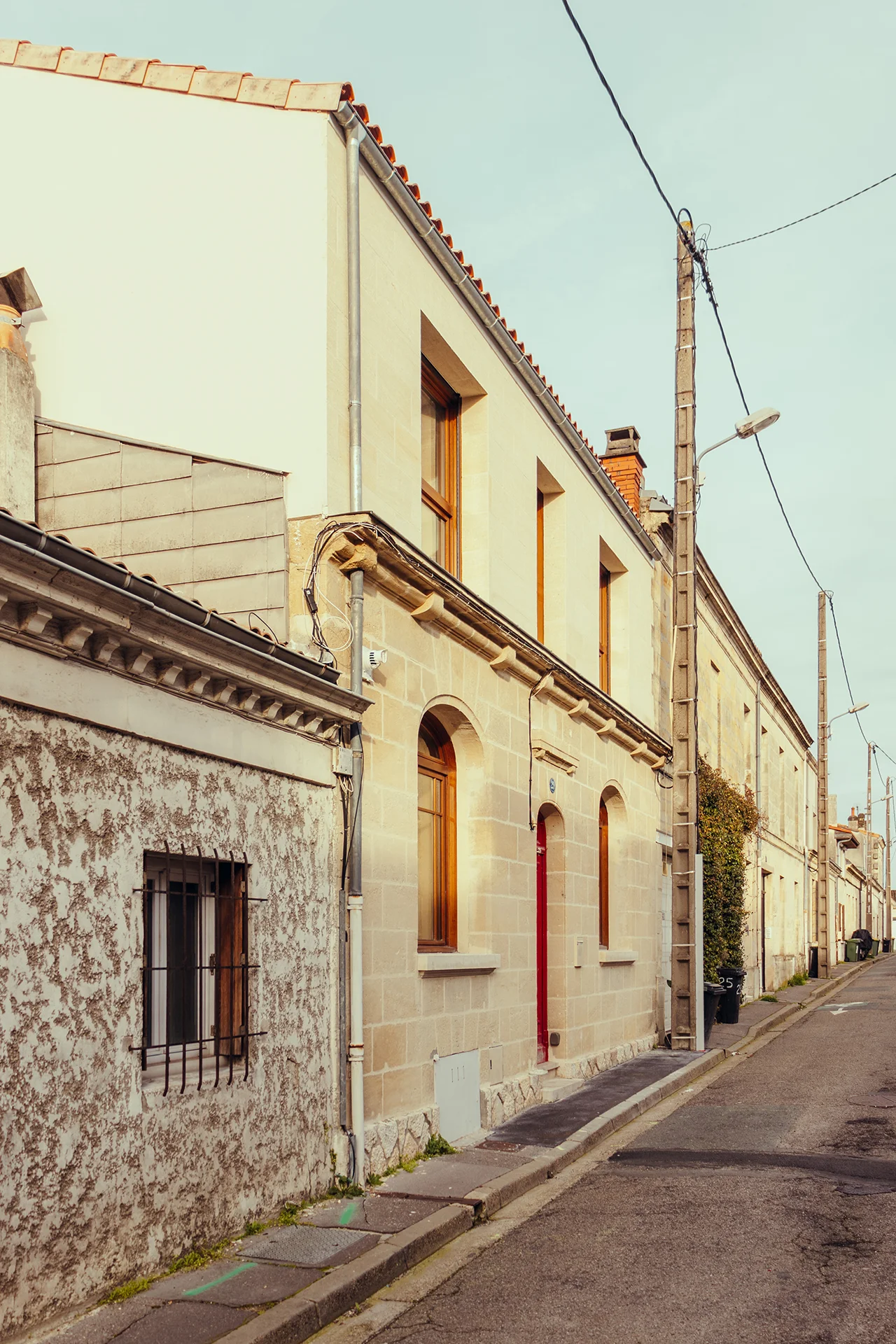 Vue de la surélévation en pierre rue Bernard à Bègles dans la rue pour voir l'intégration du projet, mur pignon en enduit minéral ton pierre